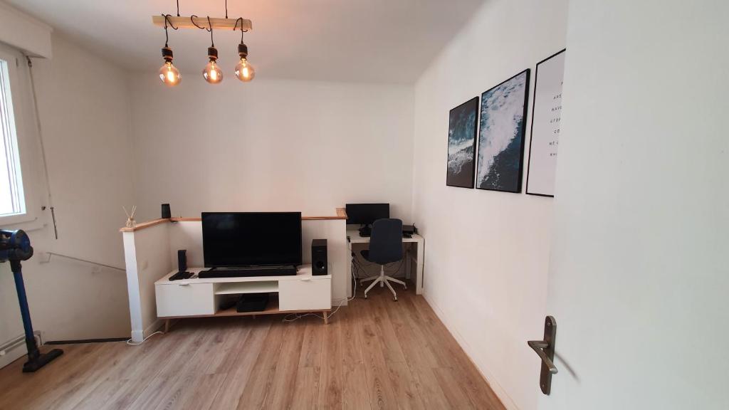 Zimmer mit einem Schreibtisch, einem TV und einem Computer. in der Unterkunft Joli T2- centre ville - Parking gratuit - WIFI in Dunkerque