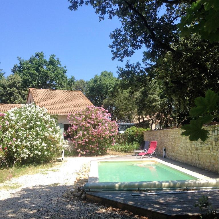 - une piscine dans une cour avec une chaise rouge dans l'établissement Villa charmante à Arpaillargues-et-Aureillac avec piscine privée, à Arpaillargues-et-Aureillac