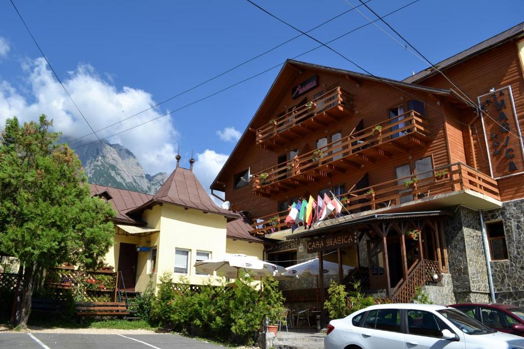 a building with a hotel with mountains in the background at Casa Magica Busteni in Buşteni