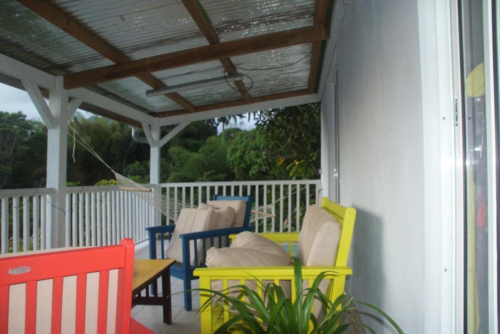 a porch with chairs and a table and awning at Studio avec vue sur la mer terrasse amenagee et wifi a Fort de France a 8 km de la plage in Fort-de-France