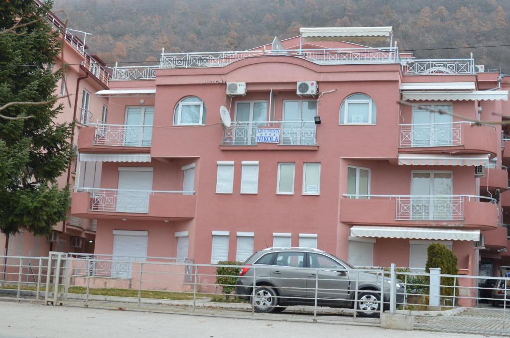 a car parked in front of a pink building at Nikola Apartments in Ohrid