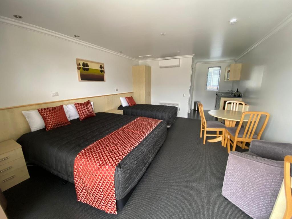 1 dormitorio con 1 cama, mesa y sillas en Grove Park Motor Lodge, en Blenheim