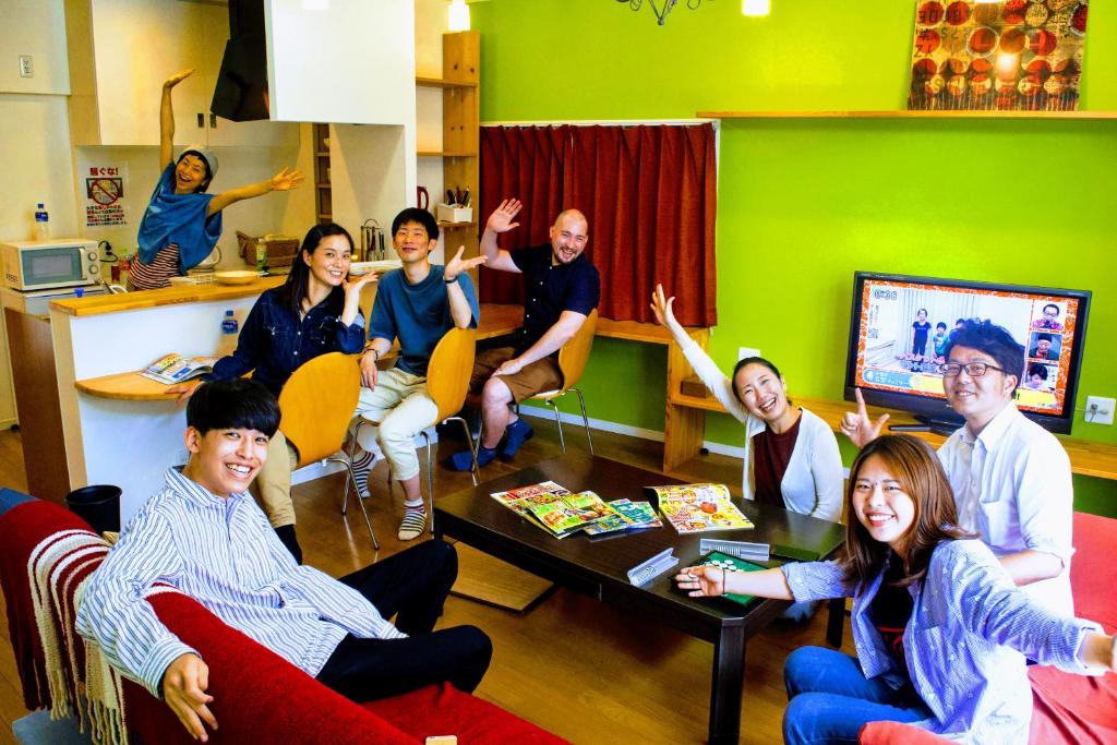 高知市にあるゲストハウス ルルル 最大12名可 合宿 大家族 団体旅行にオススメの手を上げて座る人々