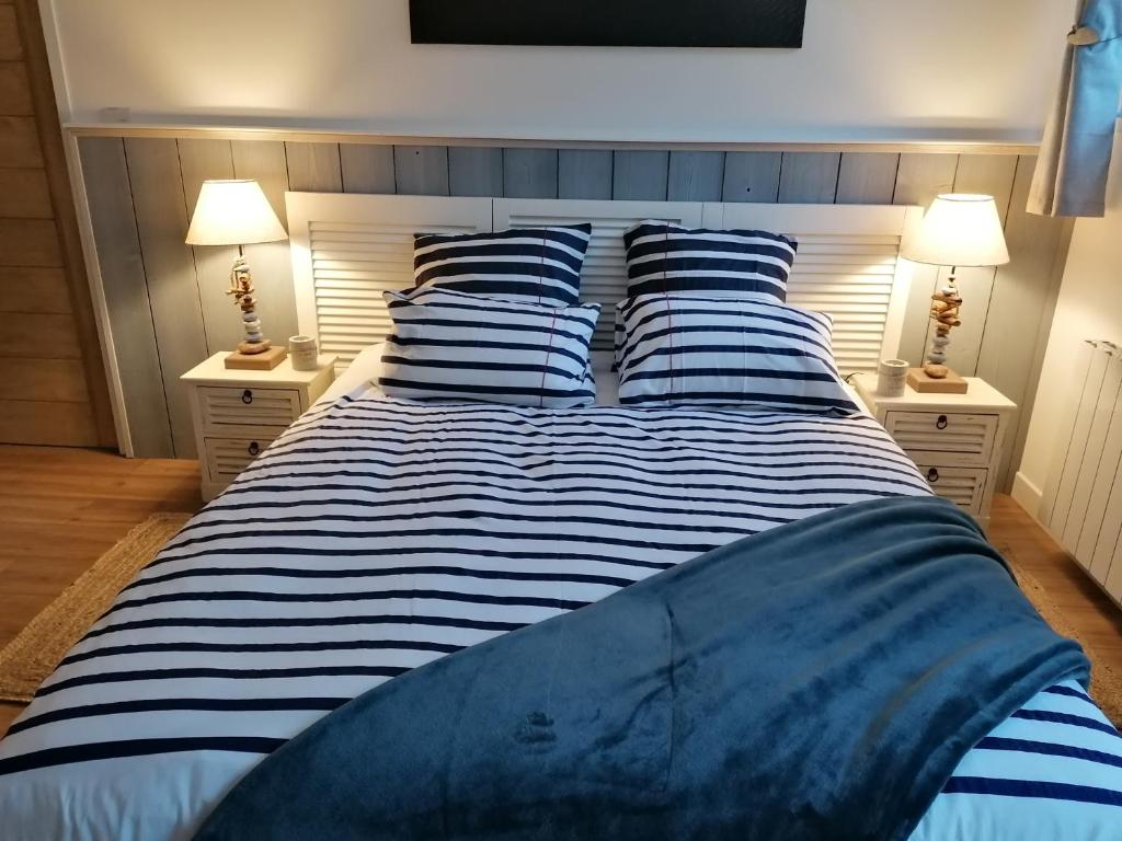 un grande letto con lenzuola e cuscini a righe blu e bianche di Chambre Studio Les Deux Vagues a Sangatte