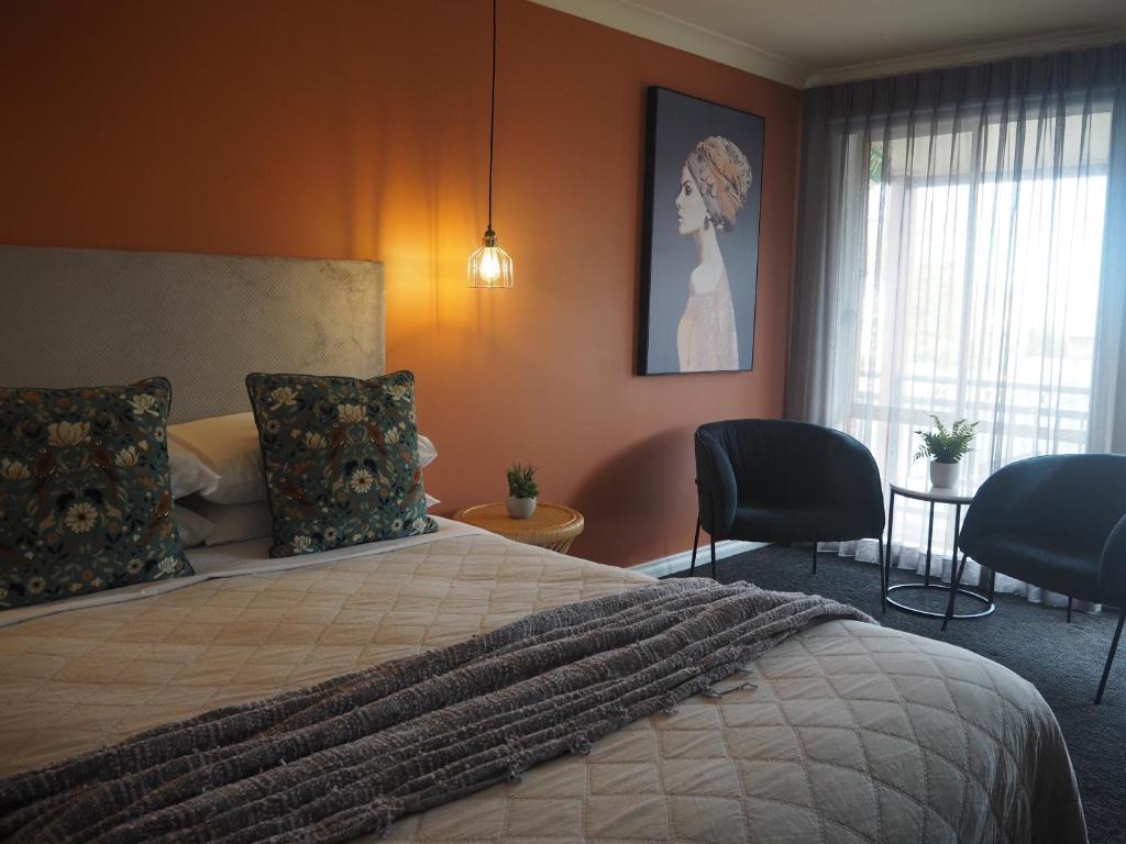 1 dormitorio con 1 cama, 2 sillas y ventana en Alexandra Place en Bendigo
