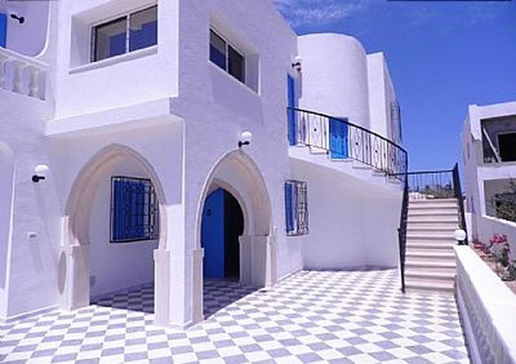 een groot wit gebouw met een geruite vloer bij 3 bedrooms house at Djerba Midoun 800 m away from the beach with terrace and wifi in Taguermess