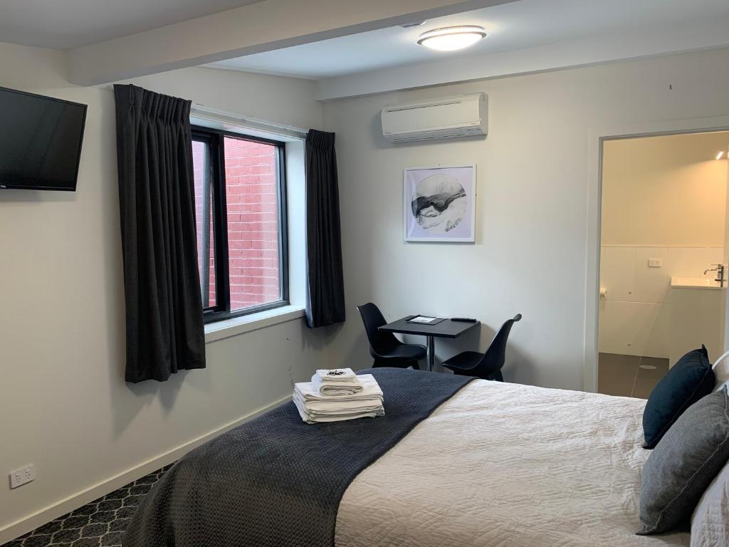 1 dormitorio con cama, escritorio y ventana en Queens Arms Hotel en Longford