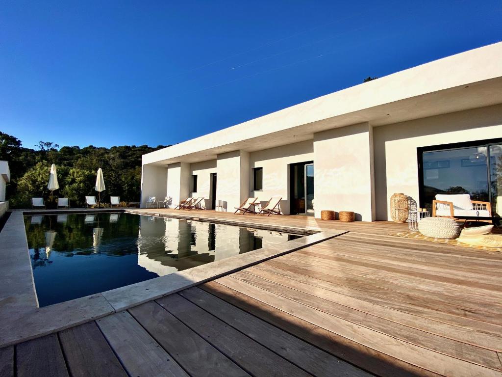 a house with a swimming pool and a wooden deck at Villas de standing avec magnifique vue mer et piscines privées, Sagone in Sagone