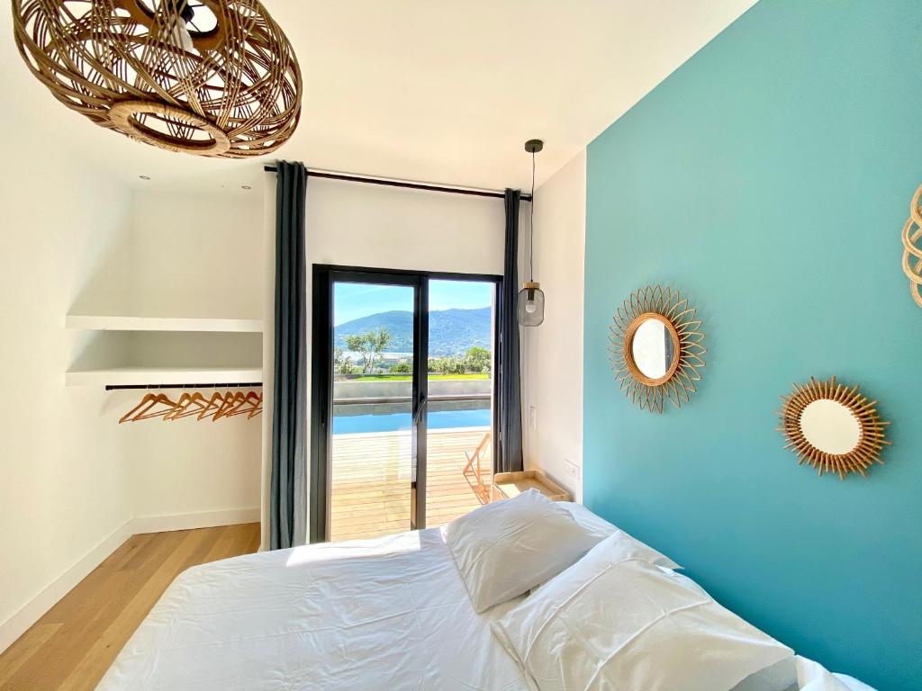 a bedroom with a bed with a blue wall at Villas de standing avec magnifique vue mer et piscines privées, Sagone in Sagone