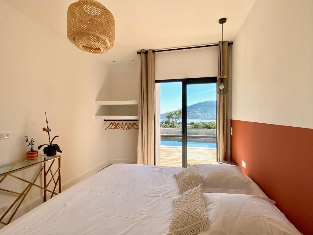 a bedroom with a bed and a large window at Villas de standing avec magnifique vue mer et piscines privées, Sagone in Sagone