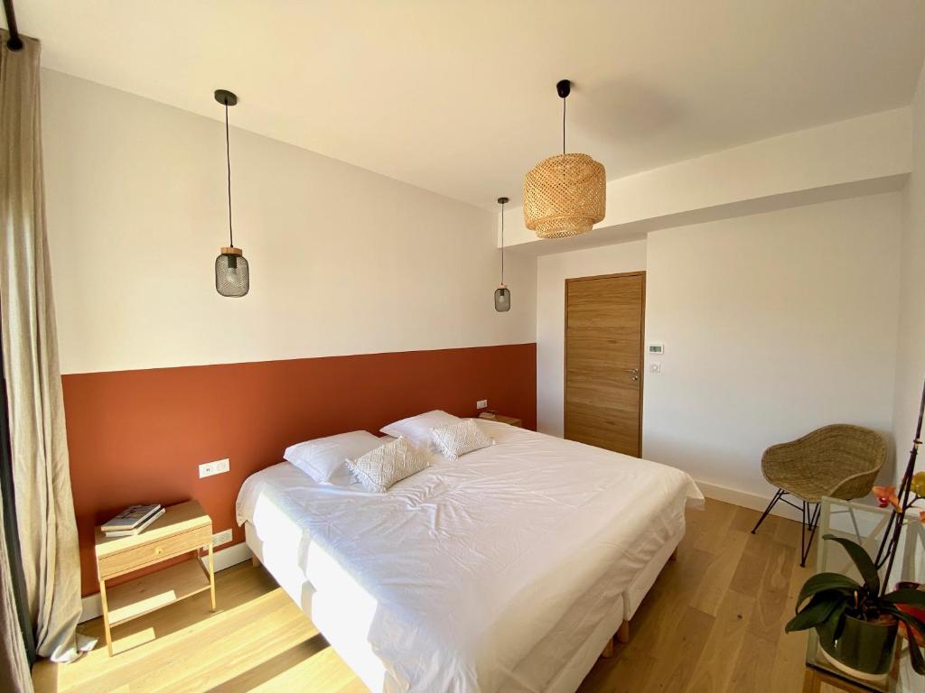 a bedroom with a white bed with a red wall at Villas de standing avec magnifique vue mer et piscines privées, Sagone in Sagone