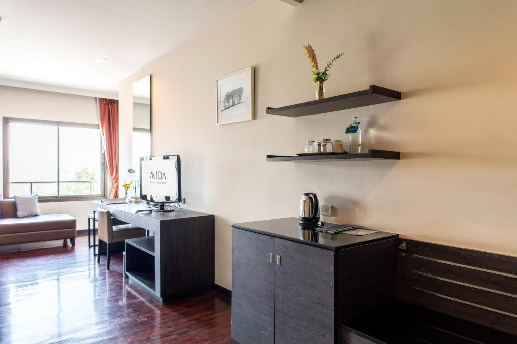 A compact work area with a desk, monitor and kitchenette-style storage.