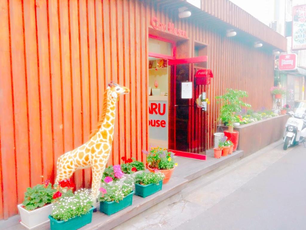 eine Giraffe vor einem Gebäude mit Pflanzen in der Unterkunft Naru Hostel Korea in Seoul