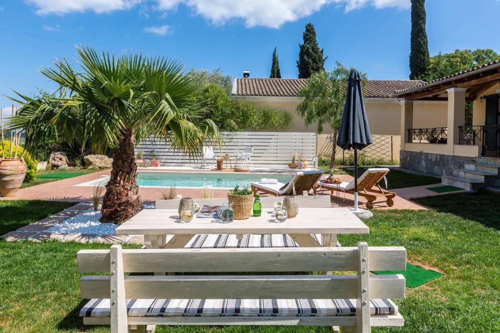 un patio con mesa, sillas y piscina en Villa Caramel, en Ágios Ioánnis