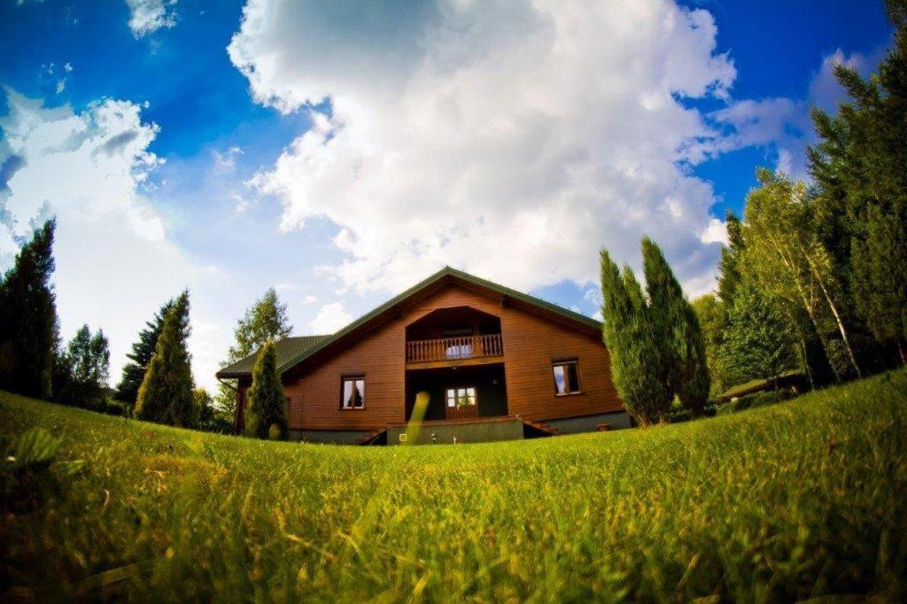 a house on a hill with a green field in front at Apartamenty Pod Gruszką 