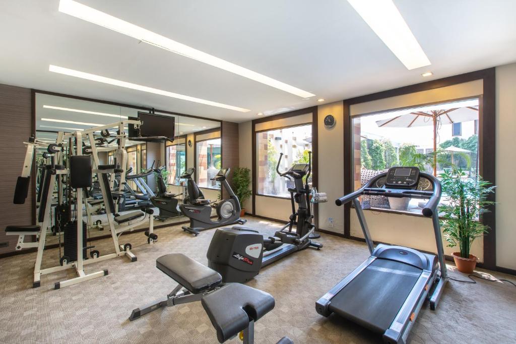 A mirrored hotel gym with cardio machines and a multi-station weight machine.