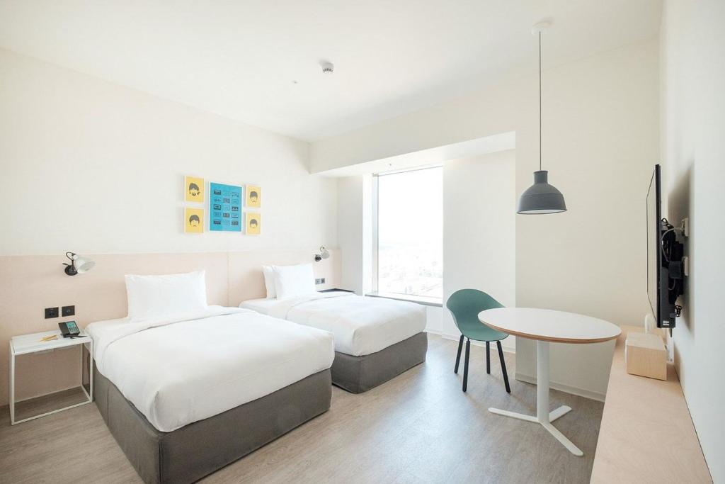 a hotel room with two beds and a table at amba Taipei Songshan in Taipei