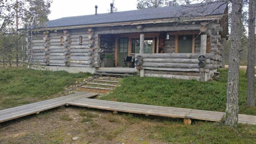 a log cabin with a porch and stairs in front of it at Kuukkeli Log Houses Villa Aurora "Pupula" in Saariselka