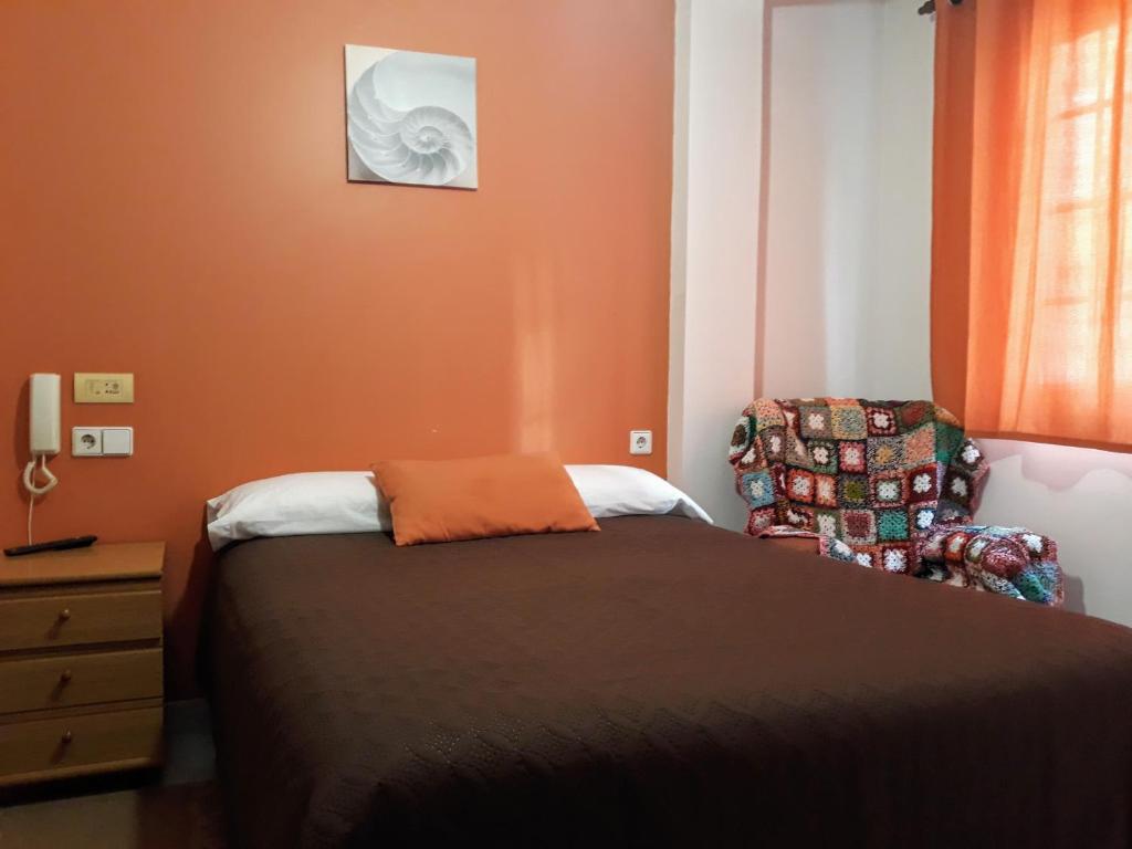 1 dormitorio con 1 cama y 1 silla en Porta Nova Apartamentos, en Ferrol