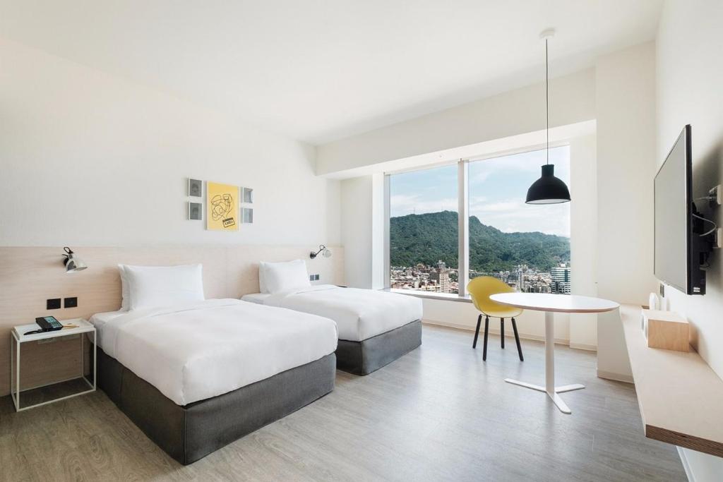 a hotel room with two beds and a table at amba Taipei Songshan in Taipei