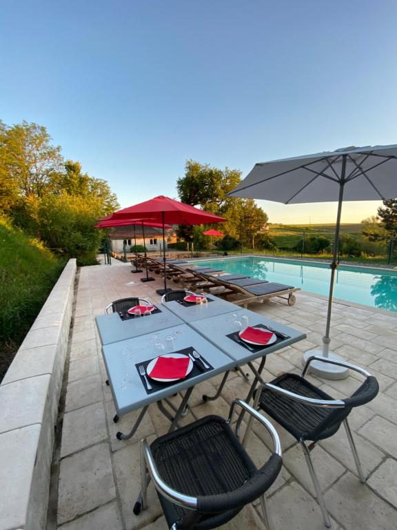 una mesa azul con sillas y una sombrilla junto a una piscina en Domaine de La Michelle, en Madaillan