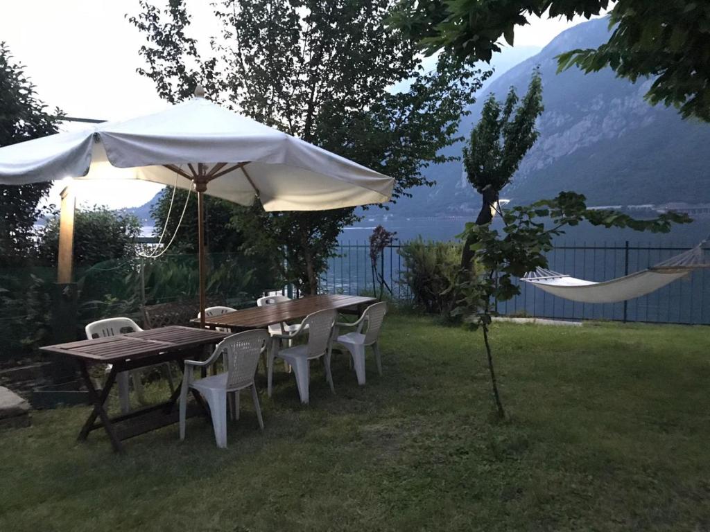 un tavolo e sedie sotto un ombrellone nell'erba di L For Lake a Mandello del Lario