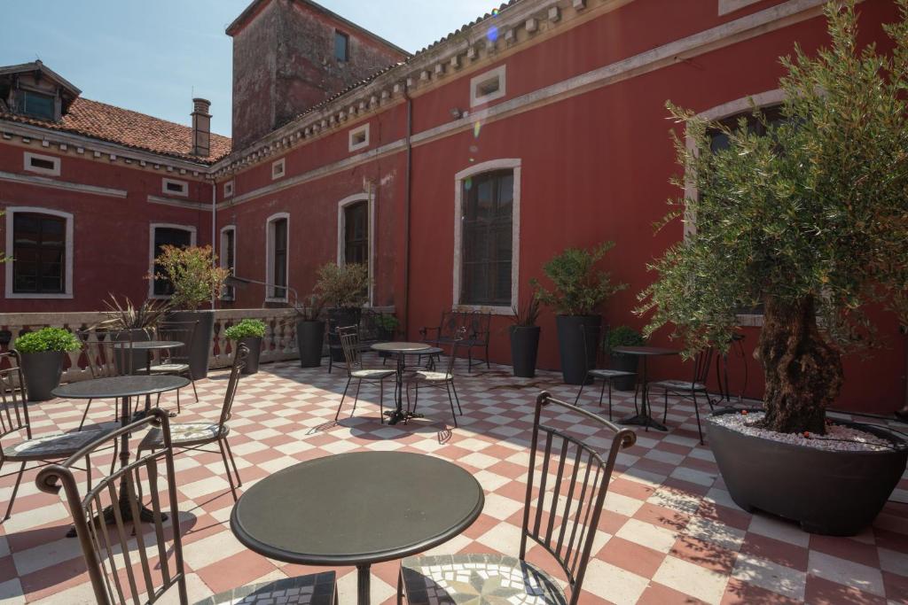 a patio with tables and chairs on a red building at Hotel Palazzo Martinelli Dolfin in Venice