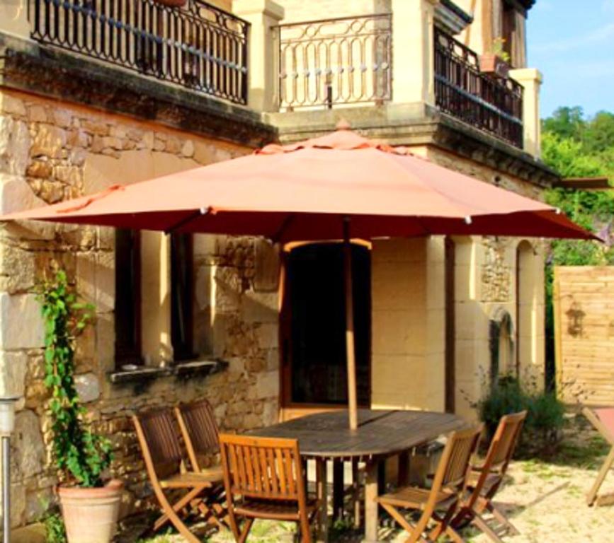 a table with an umbrella in front of a building at Maison de 2 chambres avec piscine partagee jardin amenage et wifi a Saint Cybranet in Saint-Cybranet