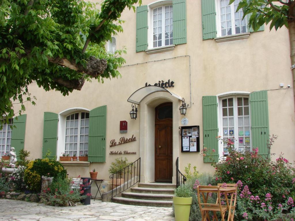 um edifício com persianas verdes e uma porta de madeira em Hôtel Le Siècle em Mazan