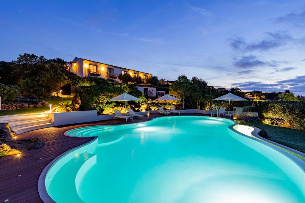 a swimming pool at night with a house in the background at Baga Baga in Castelsardo