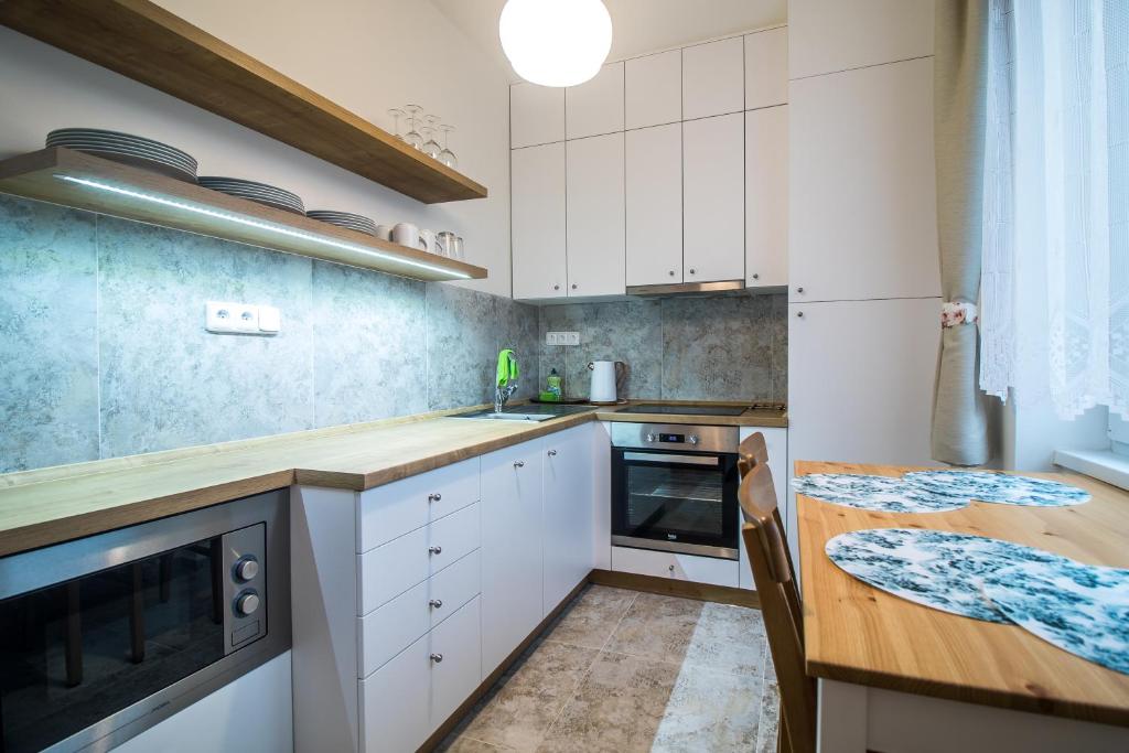 una cucina con armadi bianchi e tavolo in legno di apartmán v bytovém domě Turnov a Turnov
