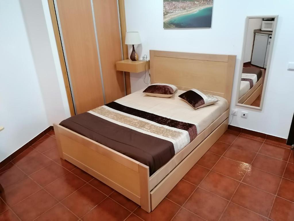 um pequeno quarto com uma cama num quarto em Estúdio - Nazaré na Nazaré