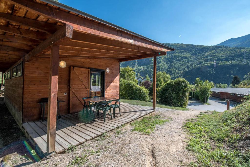 a cabin with a table and chairs on a deck at Les Chalets by Le Marintan in Saint-Michel-de-Maurienne