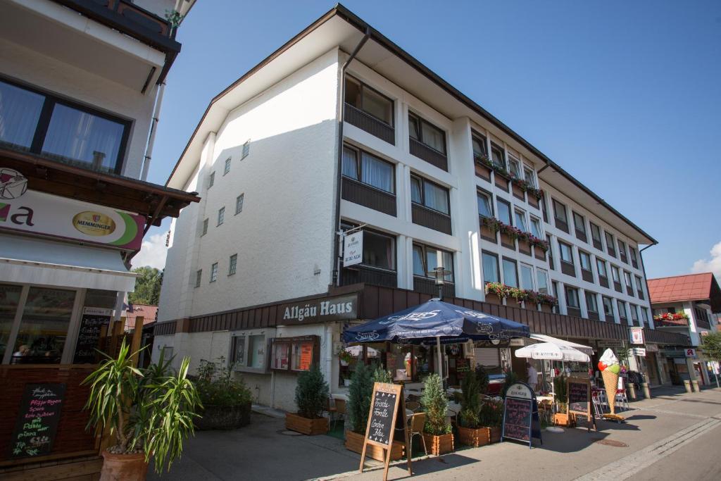 - un bâtiment dans une rue de la ville avec des tables et des parasols dans l'établissement Ferienwohnung Hillgruber, à Oberstdorf