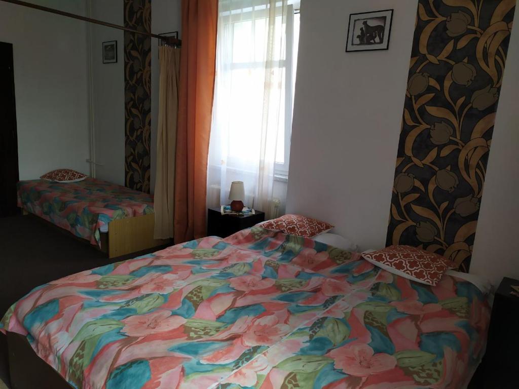 a bedroom with a bed with a colorful comforter and a window at Diamant in Karlovy Vary