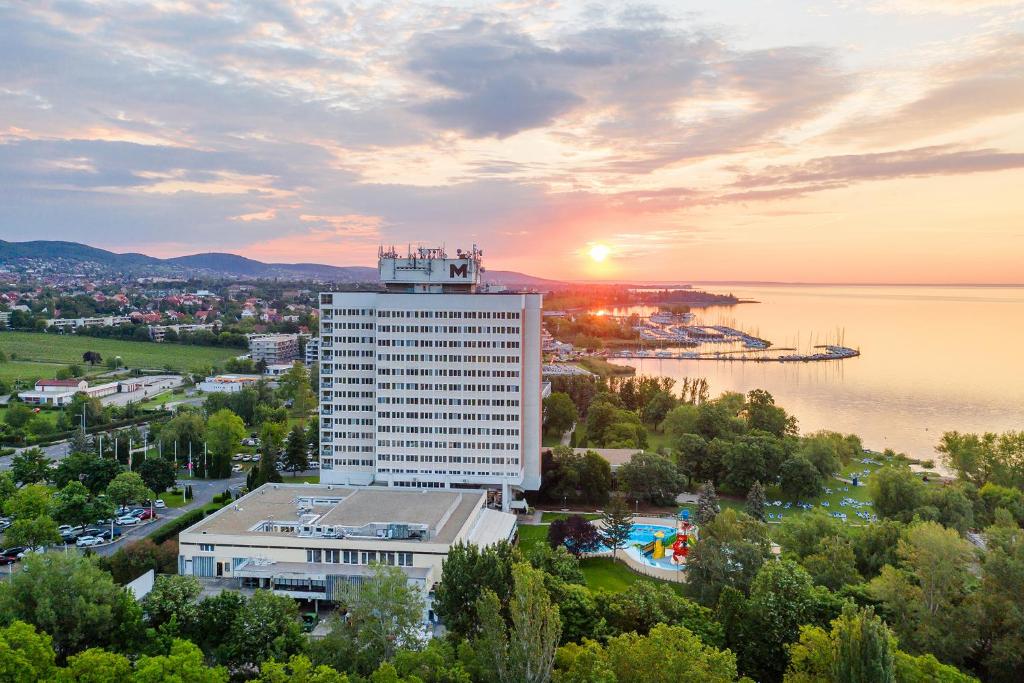 un edificio alto con una puesta de sol en el fondo en Danubius Hotel Marina en Balatonfüred