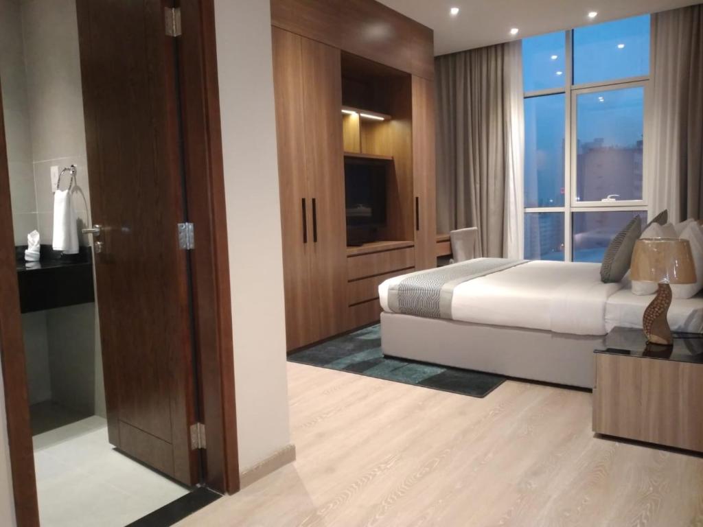 um quarto com uma cama e uma grande janela em Eden Garden Hotel Apartment em Manama