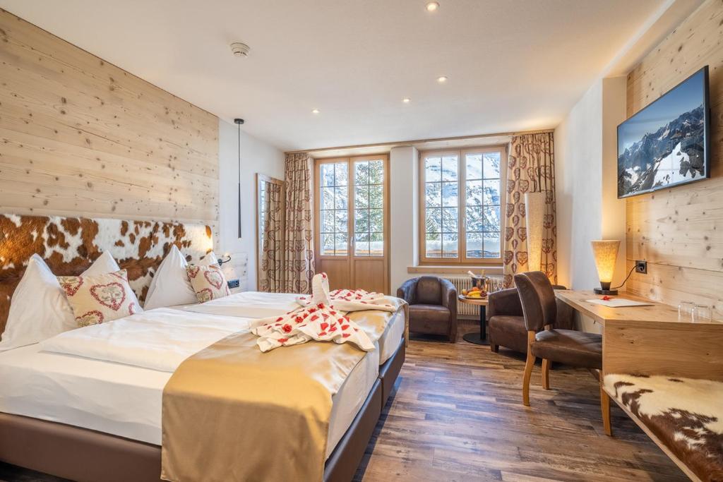 a hotel room with a large bed and a large window at Hotel Alpenruh in Mürren