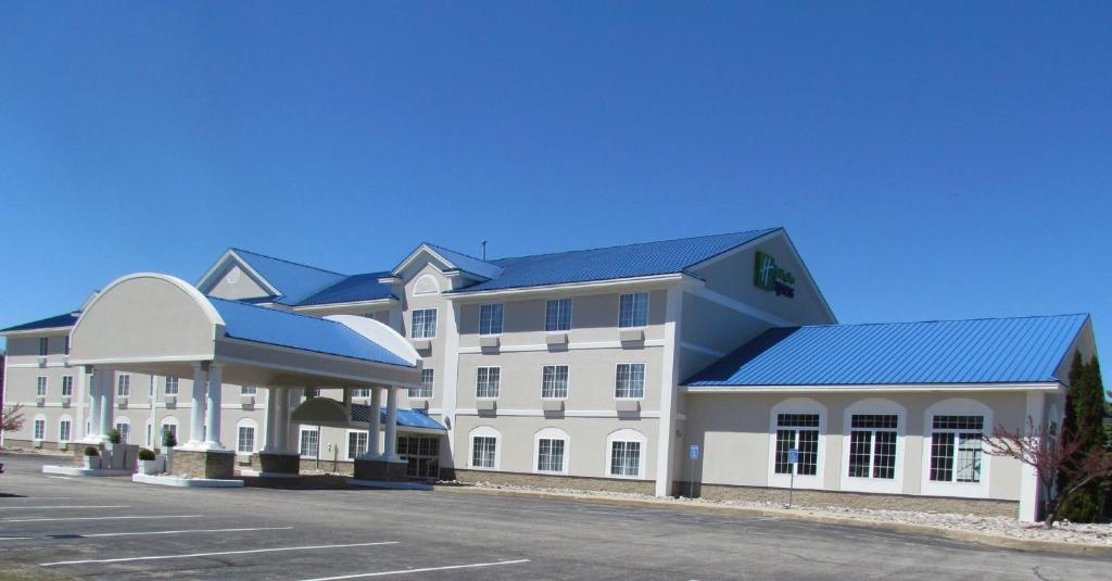 a large white building with a blue roof at Holiday Inn Express Hotel & Suites Cadillac, an IHG Hotel in Cadillac