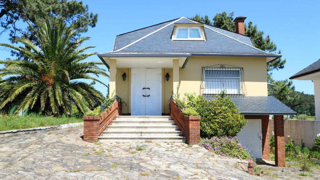 a yellow house with a white door and stairs at 5 bedrooms house at Boiro 130 m away from the beach with sea view and enclosed garden in Boiro