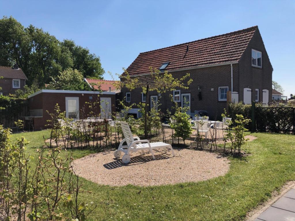 a garden with a bench in front of a house at Camping 7Huizen aan Zee in Scharendijke
