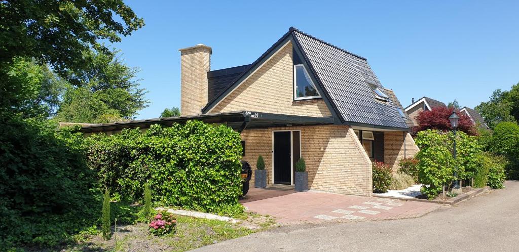 une maison en briques brunes avec un toit noir dans l'établissement Lake house 21 relax accommodation iR Sauna, à Warmond