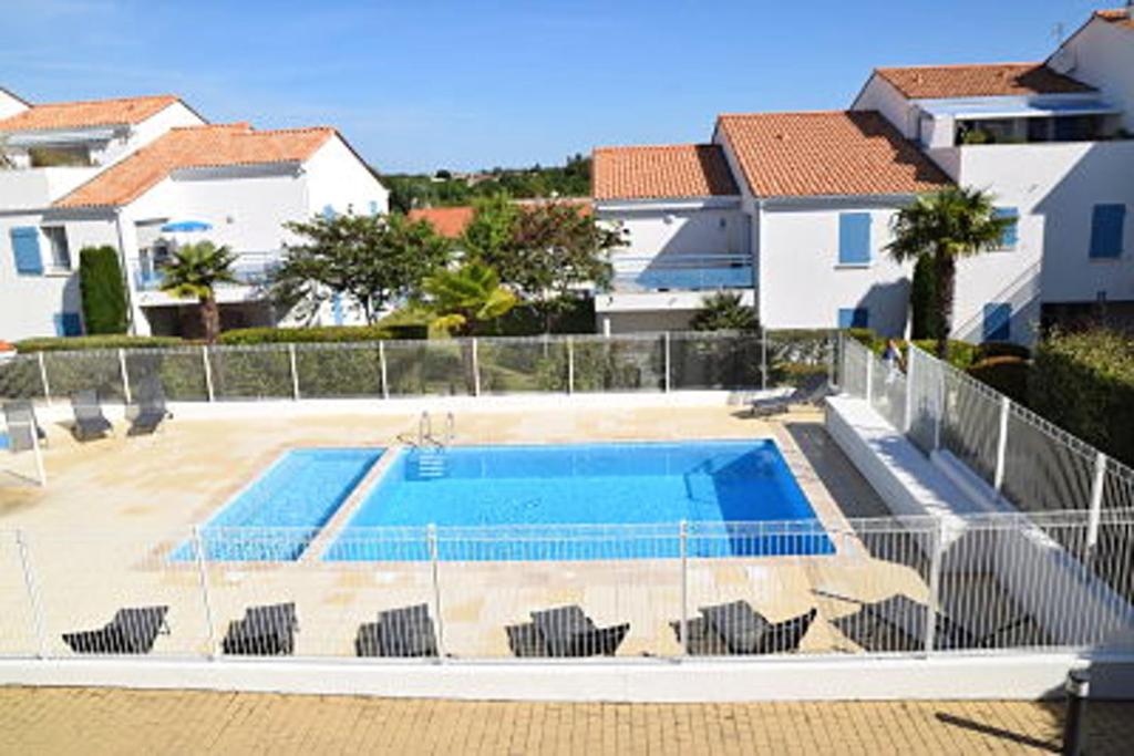 ヴォー・シュル・メールにあるMaison de 2 chambres a Vaux sur Mer a 900 m de la plage avec piscine partagee jardin clos et wifiの一部の建物に隣接するスイミングプール(椅子付)