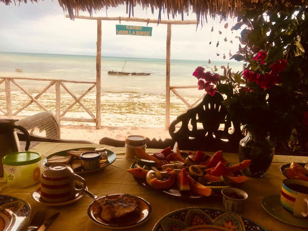 una mesa con comida y vistas a la playa en Vanilla House, en Jambiani