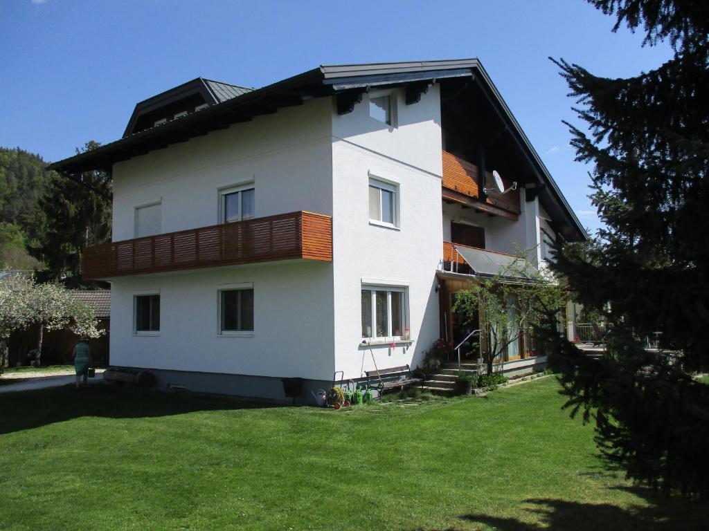 a white house with a balcony and a yard at Fewo Zak in Sankt Kanzian