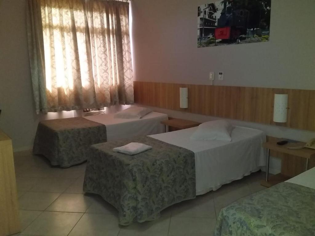 a hotel room with two beds and two tables at CHA Mime Hotel in Blumenau