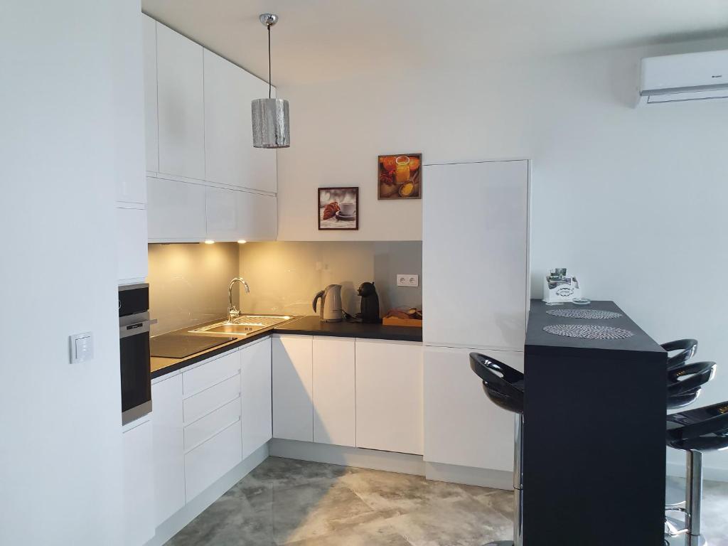 eine Küche mit weißen Schränken und einer schwarzen Arbeitsplatte in der Unterkunft Apartament na Lazurowej in Warschau