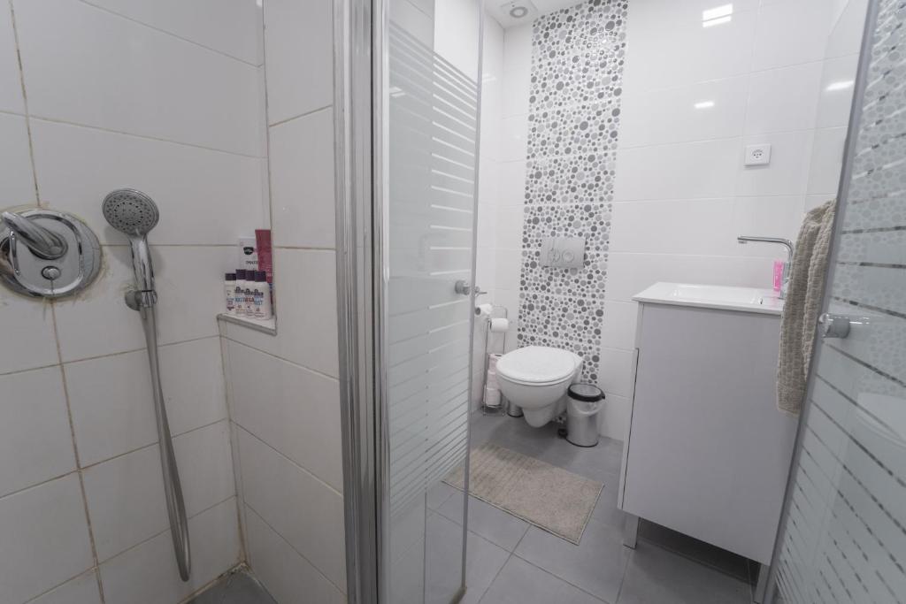 a white bathroom with a shower and a toilet at Neviot in Eilat