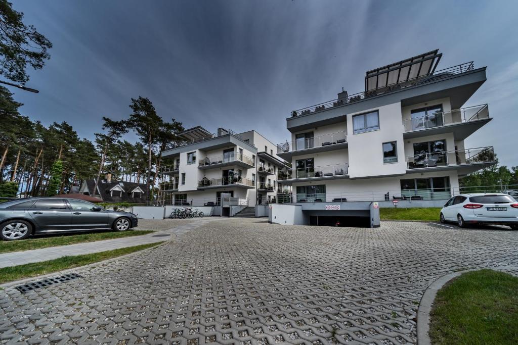 a building with two cars parked in front of it at Baltic Apartments in Pobierowo