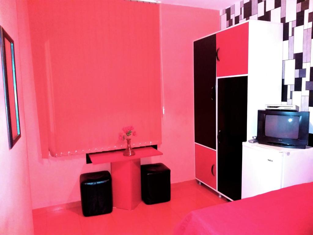 Habitación rosa con TV y pared roja. en APARTMENT LEO 2, en Varna